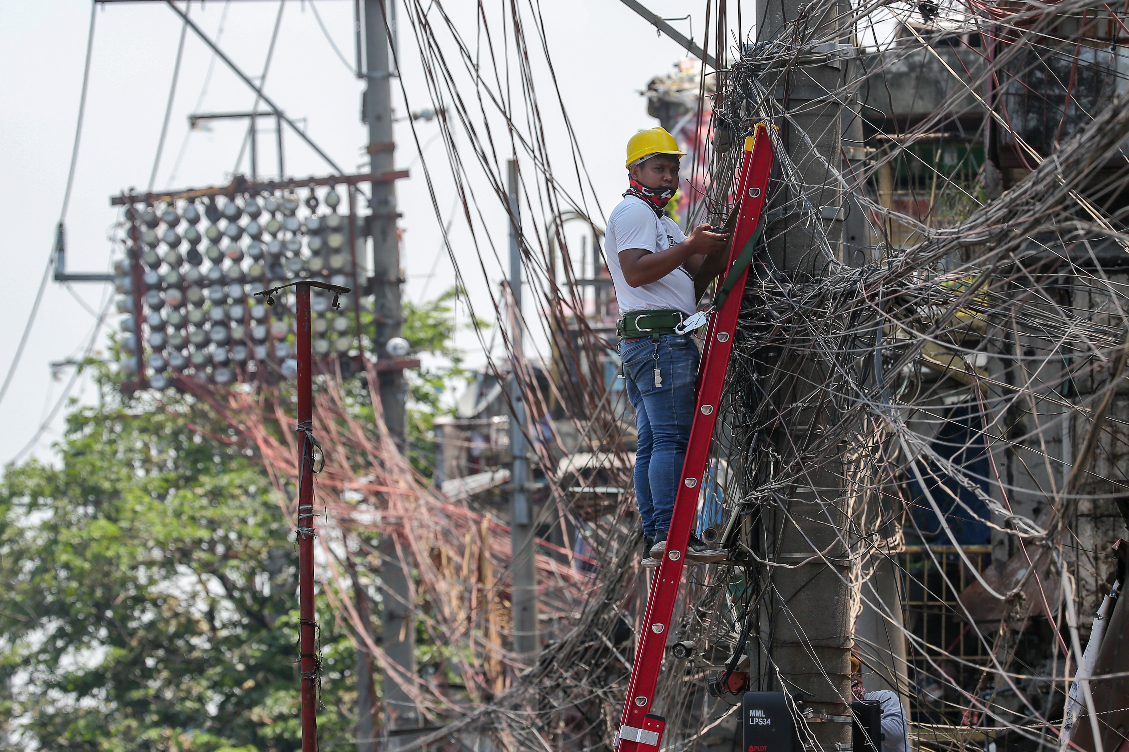 A lineman works on an electric post at the Katuparan housing project in Vitas, Tondo Manila on July 7, 2021. George Calvelo, ABS-CBN News