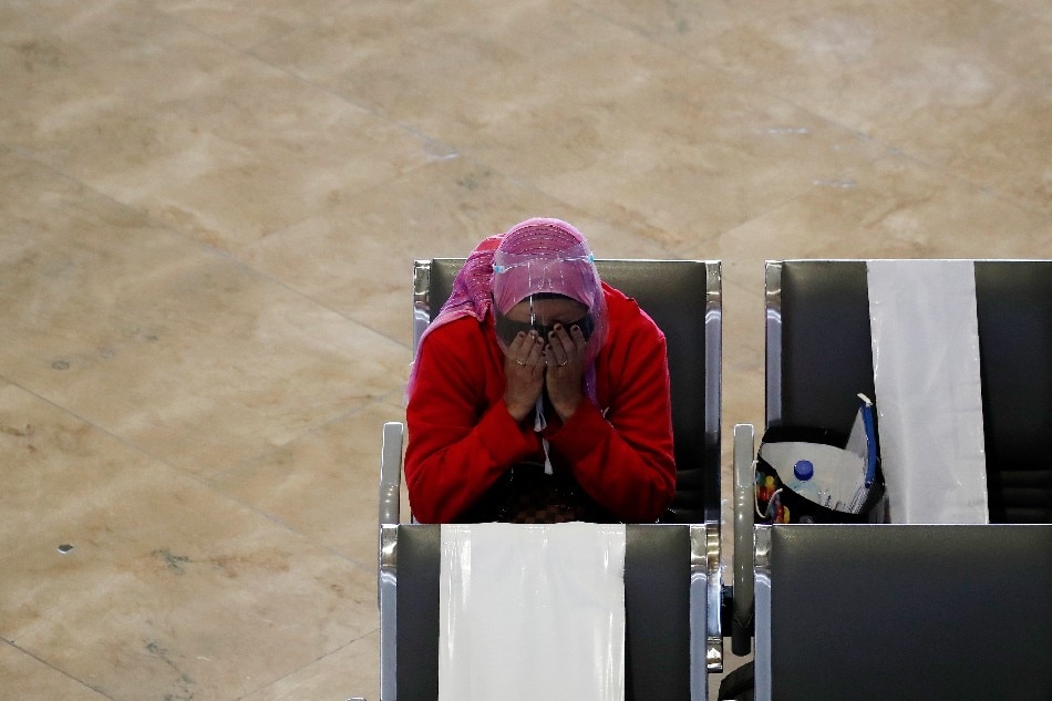 A Filipino migrant worker reacts as she waits to board an airplane at Manila's international airport on June 7, 2021. Francis R. Malasig, EPA-EFE/File