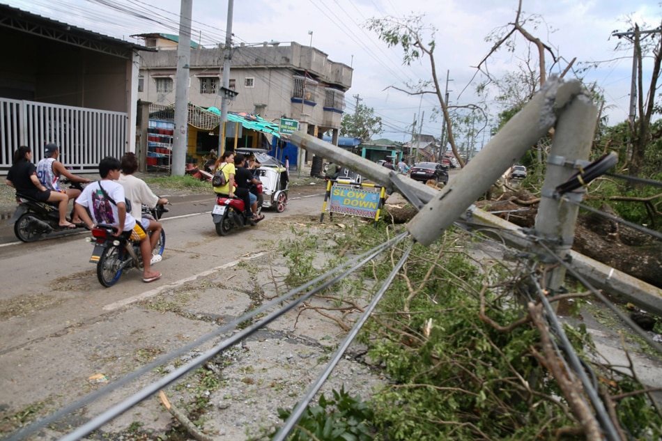 Motorists drive past toppled electric post along Barangay Kaliwa in Gapan, Nueva Ecija on Sept. 26, 2022. Jonatahan Cellona, ABS-CBN News