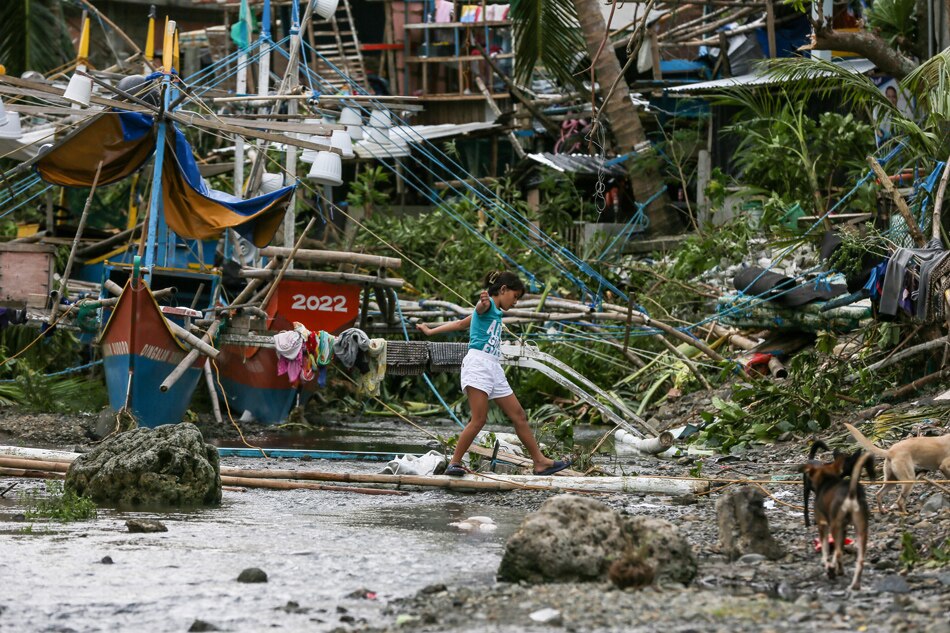 A child walsk past moored boats and damaged structures in tihe seaside community of Barangay Paltic in Dingalan Aurora on September 26, 2022. Jonathan Cellona, ABS-CBN News