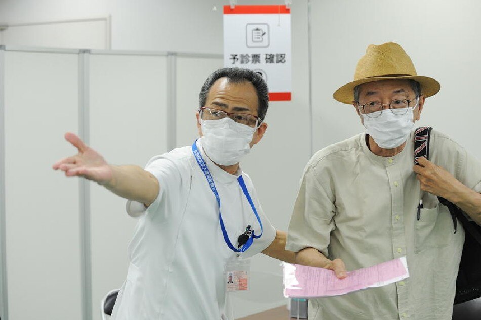 A medical worker guides an elderly person at a mass vaccination site in Tokyo, Japan, 09 June 2021, as the Japan Self-Defense Forces (JSDF) starts a large scale inoculation of COVID-19 vaccine. EPA-EFE/DAVID MAREUIL / POOL