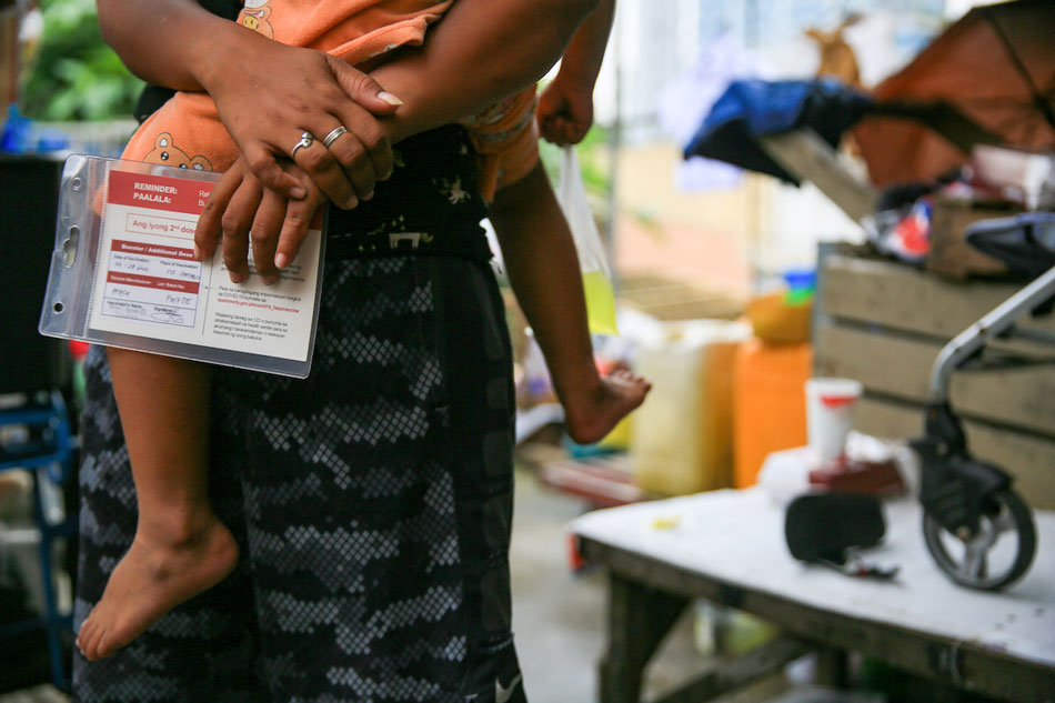 A mother carries her child after being inoculated with a COVID-19 booster shot in Scout Santiago in Quezon City on September 29, 2022. Jonathan Cellona, ABS-CBN News/file 