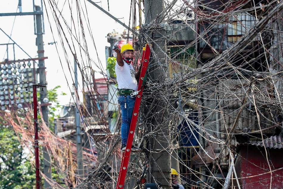 A lineman works on an electric post at the Katuparan housing project in Vitas, Tondo Manila on July 7, 2021. George Calvelo, ABS-CBN News/File