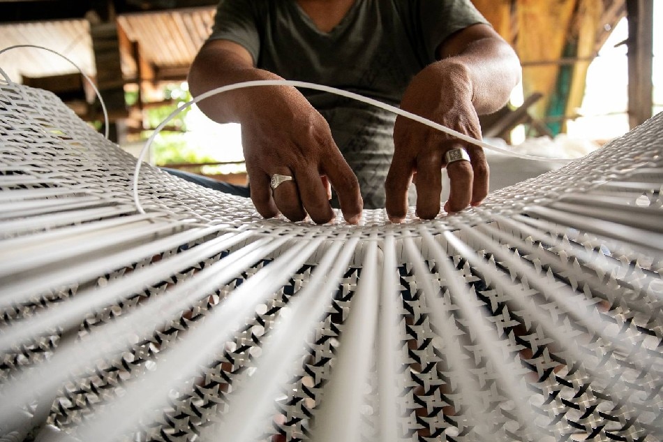 A worker uses plastic rattan to assemble a chair inside a furniture shop in Villaba town in the province of Leyte, south of Manila, Philippines. Photo by Basilio Sepe / Oxfam Pilipinas