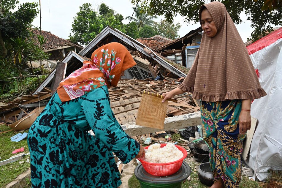 Women cook beside the rubble of a collapsed house in Cugenang, Cianjur on Nov. 23, 2022, following a 5.6-magnitude earthquake on Nov. 21. Adek Berry, Agence France-Presse