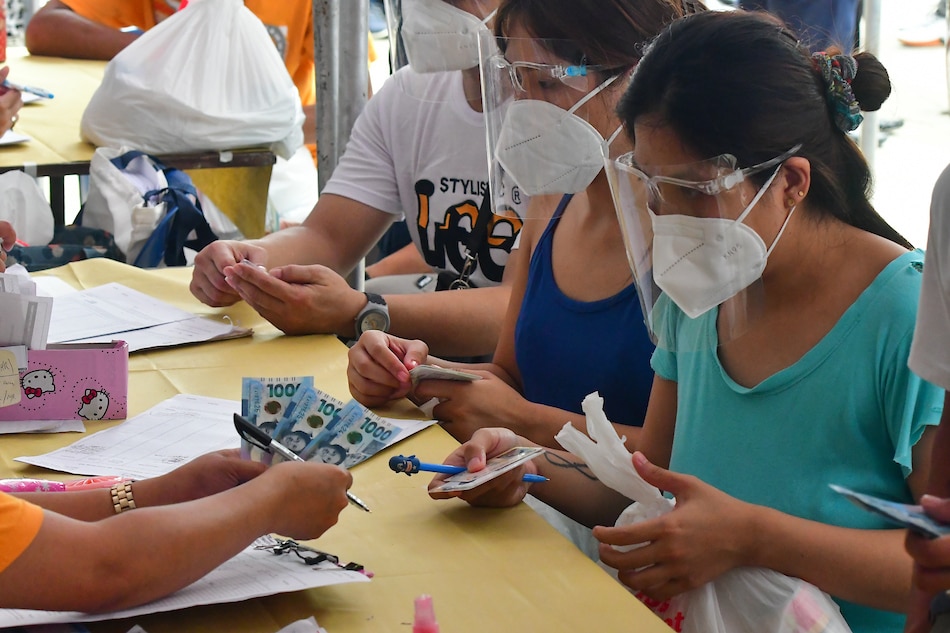 Residents of Barangay Manggahan, Pasig City receive food packs from local government unit along with the cash aid under the DSWD's social amelioration program on Aug. 12, 2021, amid the enhanced community quarantine under Metro Manila. Mark Demayo, ABS-CBN News/File