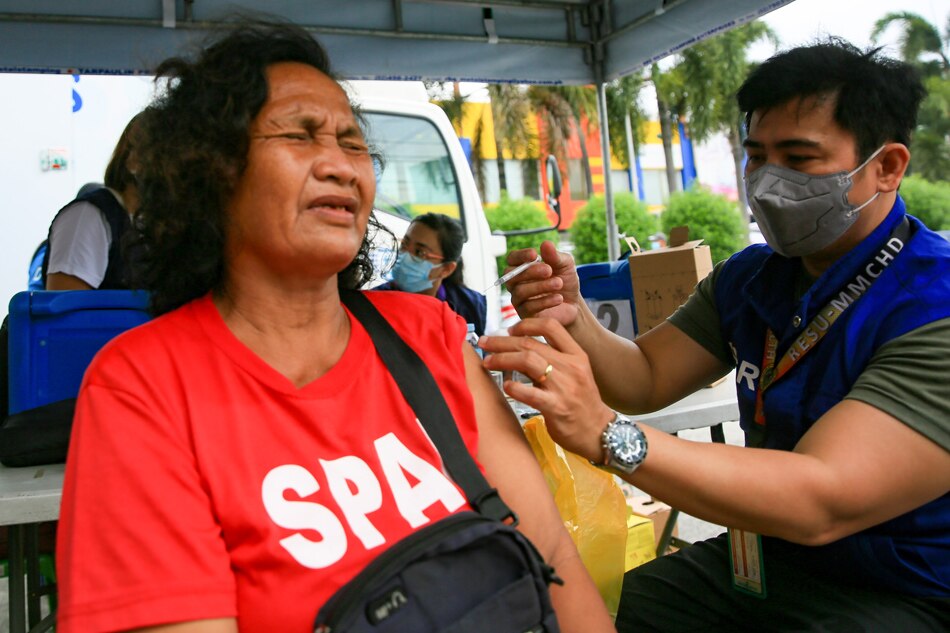 A health worker inoculates a woman with a COVID-19 booster shot along Scout Santiago Street in Quezon City on Sept. 29, 2022. Jonathan Cellona, ABS-CBN News/File