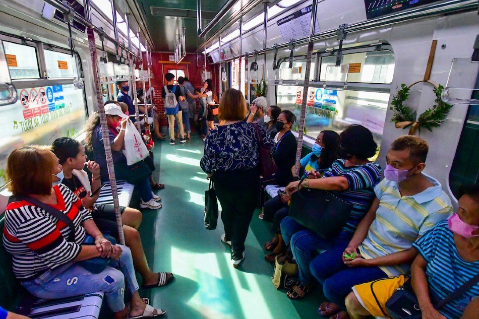 Commuters ride the LRT-1's new Christmas Train featuring classic and retro-pop music-themed decals in Quezon City on December 5, 2022. The rail line resumed their tradition of Christmas-themed trains after a hiatus in 2020. Mark Demayo, ABS-CBN News