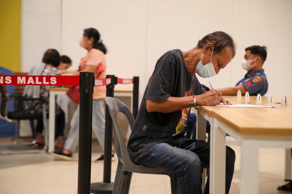 A resident fills out a form for voter’s registration at the designated Commission on Elections desk at a mall in Manila on Dec. 12, 2022. Jonathan Cellona, ABS-CBN News/file