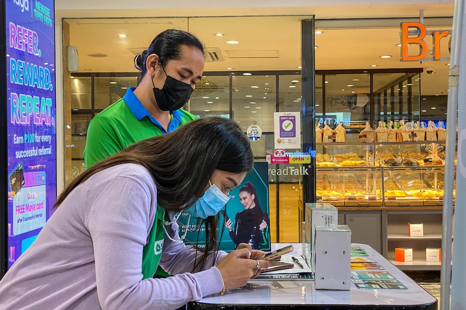 Sales representatives of telecommunications company assist clients in registering their prepaid SIM at the gadgets section in Greenhills Shopping Center in San Juan City on December 27, 2022. Jonathan Cellona, ABS-CBN News