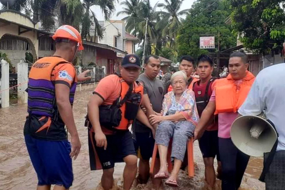 A handout photo made available by the Philippine Coast Guard (PCG) shows its personnel carrying an elderly woman at a flooded road in the town of Plaridel, Misamis Occidental province, Dec. 26, 2022. EPA-EFE/Philippine Coast Guard handout 