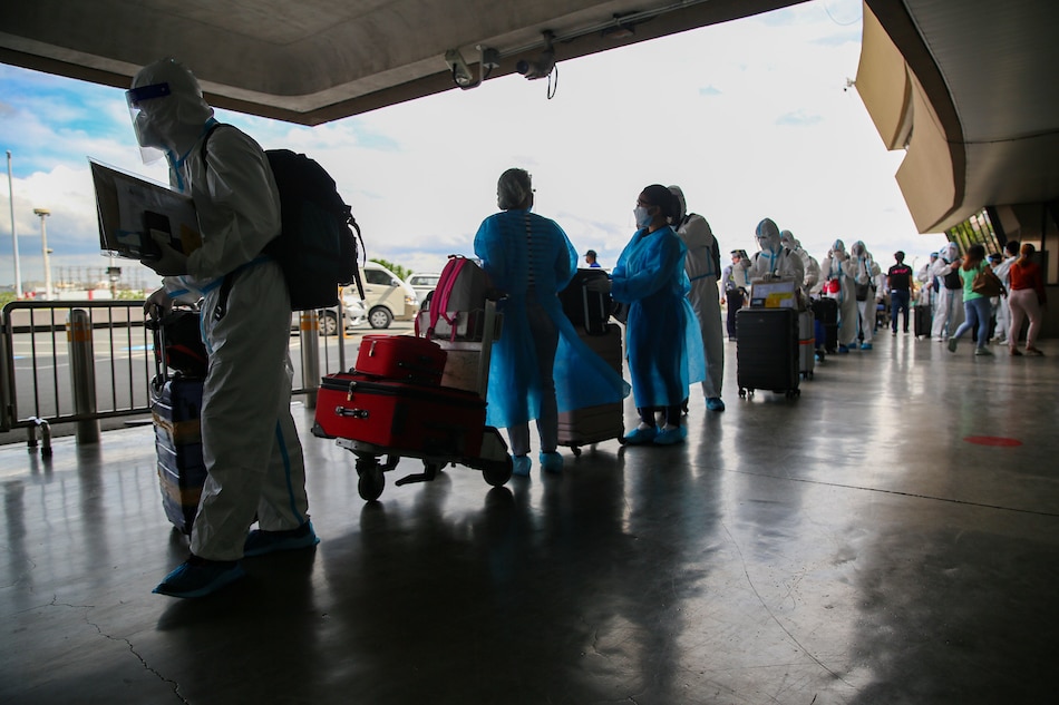 Overseas workers and travelers, some wearing personal protective suits, line up at the Terminal 1 departure area at the Ninoy Aquino International Airport (NAIA) on April 7, 2022. Jonathan Cellona, ABS-CBN News/File 