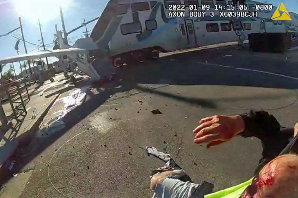 A screen grab from a police body camera video shows the pilot of a plane that crashed on railway tracks being rescued by Los Angeles Police Department officers moments before a train hit the aircraft in Los Angeles, California, US, Sunday. LAPD/Handout via Reuters