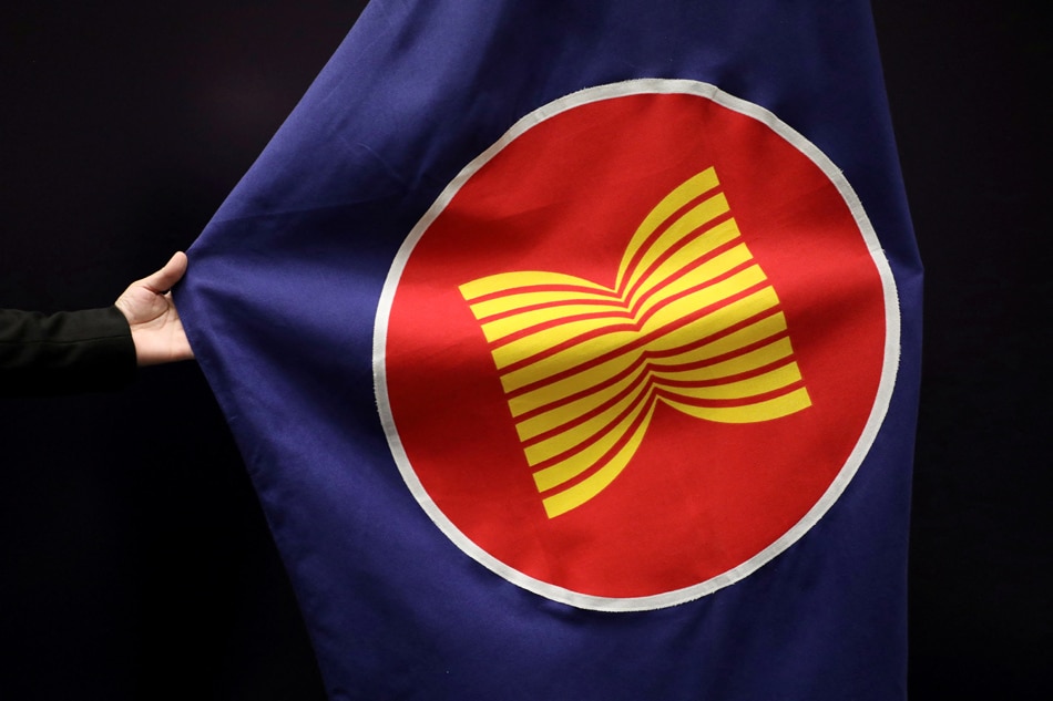 A worker adjusts an ASEAN flag at a meeting hall in Kuala Lumpur, Malaysia, October 28, 2021. Lim Huey Teng, Reuters/File