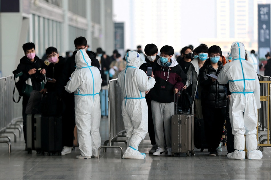 Student passengers show their nucleic acid testing results to workers in protective suits, following the coronavirus disease (COVID-19) outbreak, to enter Xian North Railway Station as the Spring Festival travel rush kicks off ahead of the Chinese Lunar New Year, in Xian, Shaanxi province, China January 17, 2022. cnsphoto via Reuters/file