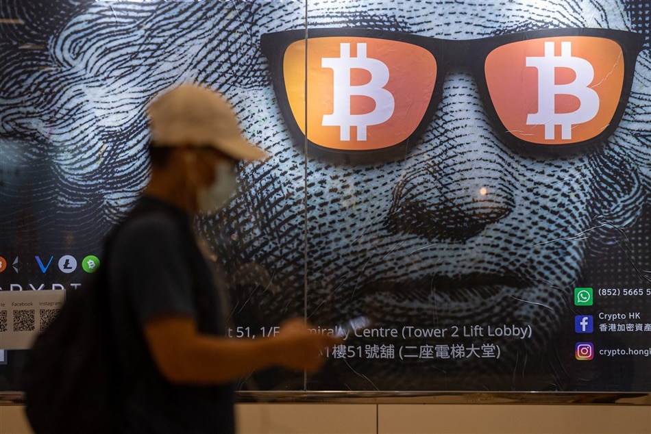 A man walks past an advertising poster for Bitcoins and cryptocurrencies in Hong Kong, China, on September 25, 2021. Jerome Favre, EPA-EFE/file