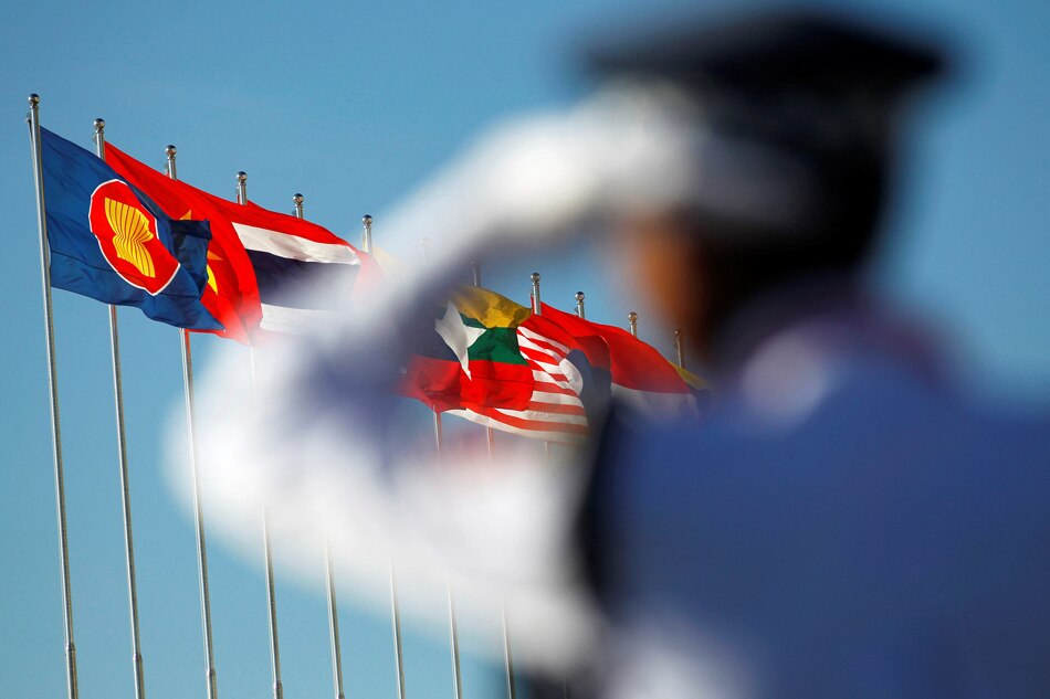 A police officer stands near national flags of ASEAN counties flags during the 25th ASEAN Summit in Myanmar International Convention Centre in Naypyitaw, November 12, 2014. REUTERS/Soe Zeya Tun/File