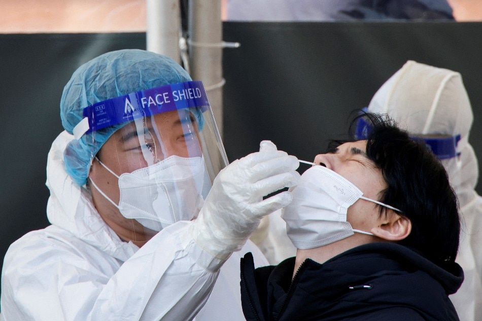 A health-care worker collects a swab sample from a man to test for COVID-19, at a temporary testing site set up at a railway station, in Seoul, South Korea, Feb. 10, 2022. Heo Ran, Reuters