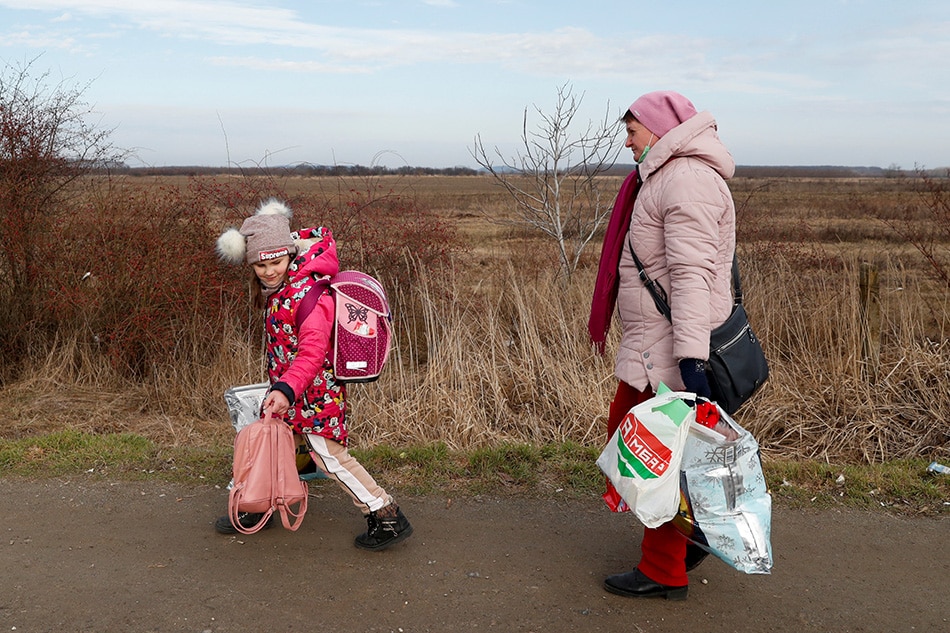 A woman and a child walk as they flee from Ukraine to Hungary, after Russia launched a massive military operation against Ukraine, at a border crossing in Beregsurany, Hungary, Feb. 25, 2022. Bernadett Szabo, Reuters 