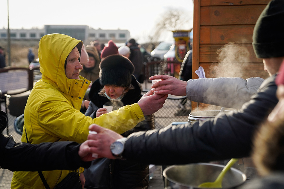 People who have recently crossed the border to flee violence in Ukraine are offered coffee in Medyka, Poland, Feb. 25, 2022. Bryan Woolston, Reuters