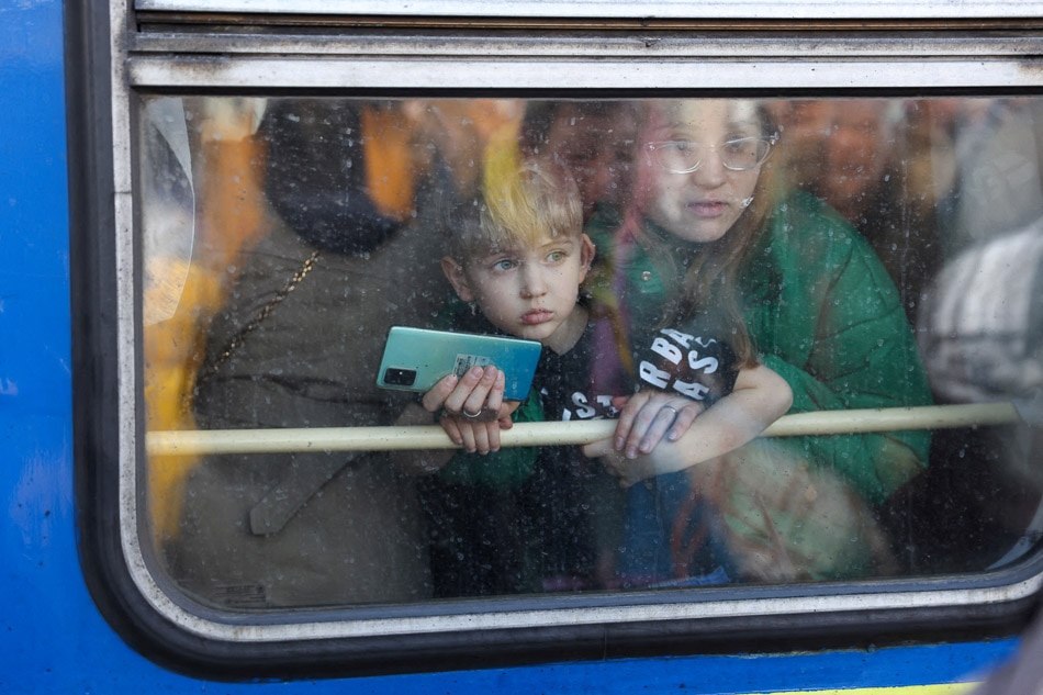 A woman and her son look out from an evacuation train from Kyiv to Lviv at Kyiv central train station, Ukraine on Feb. 25, 2022. NATO chief Jens Stoltenberg said on the same day the alliance was deploying its rapid response forces to bolster defenses on its eastern flank in the face of Russia's invasion of Ukraine. Umit Bektas/Reuters