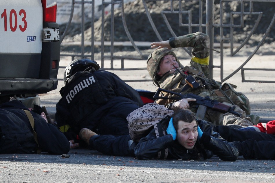 People take cover as an air-raid siren sounds, near an apartment building damaged by recent shelling in Kyiv, Ukraine February 26, 2022. Gleb Garanich, Reuters