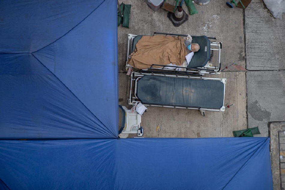 An elderly patient lies in a hospital bed at a temporary holding area outside the Caritas Medical Center in Hong Kong, China, on March 2, 2022. Jerome Favre, EPA-EFE