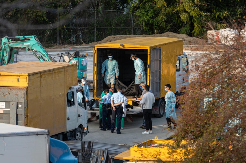 Workers move bodies from a truck into a refrigerated shipping container outside a public mortuary in Hong Kong, China, March 11, 2022. Refrigerated shipping containers have been set up outside some mortuaries, as Hong Kong struggles to cope with rising COVID-19 deaths. Jerome Favre, EPA-EFE