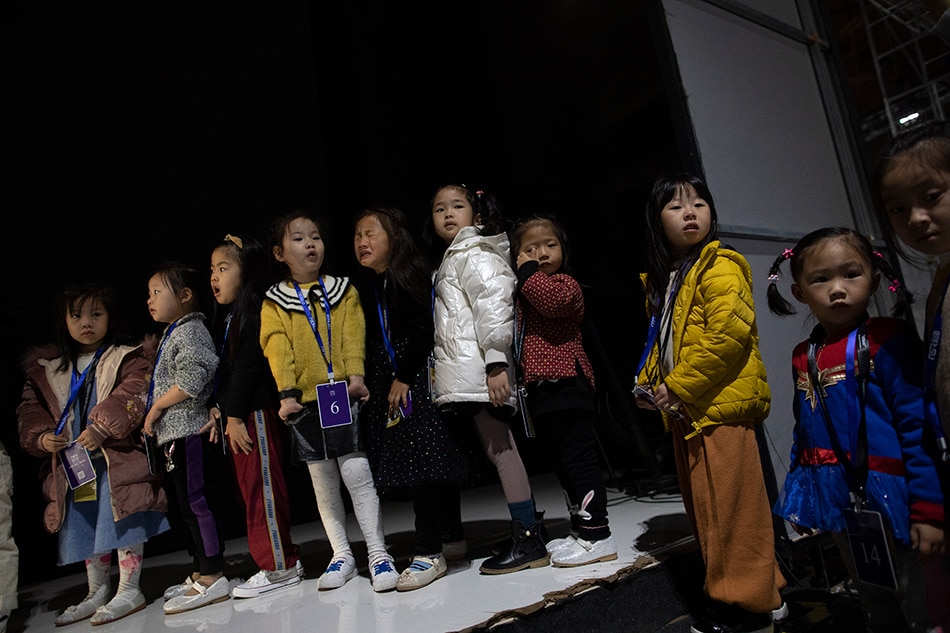 Chinese child models wait in line to go on the runway during a 5am rehearsal for local kids wear brand Van Monfe show during the China Fashion Week Kids Fashion segment at the 751 Tank venue in Beijing, China, 01 November 2019. EPA-EFE/HOW HWEE YOUNG