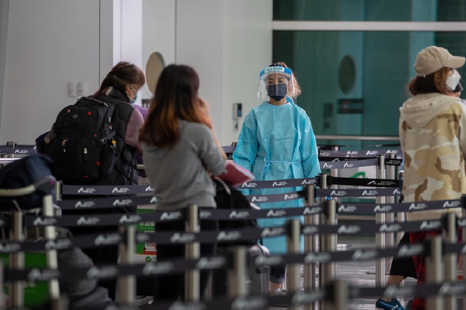 An airport worker in PPE directs travellers to their quarantine hotel after landing at Hong Kong International airport in Hong Kong, China, on March 21, 2022. Jerome Favre, EPA-EFE