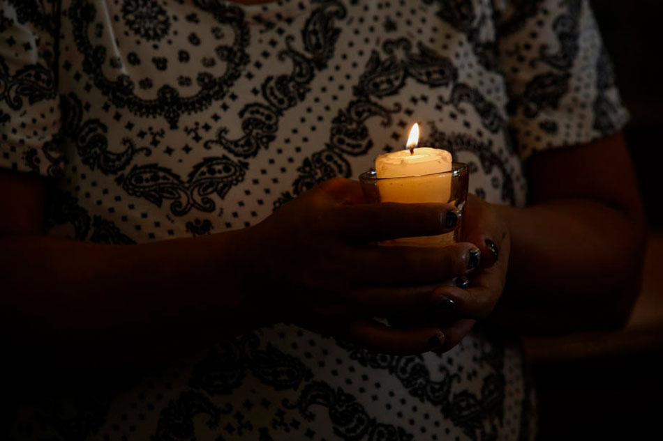 A surviving relative holds a candle during a memorial service for victims of alleged extra-judicial killings at a Catholic church in Manila, on November 15, 2021. Rolex Dela Pena, EPA-EFE