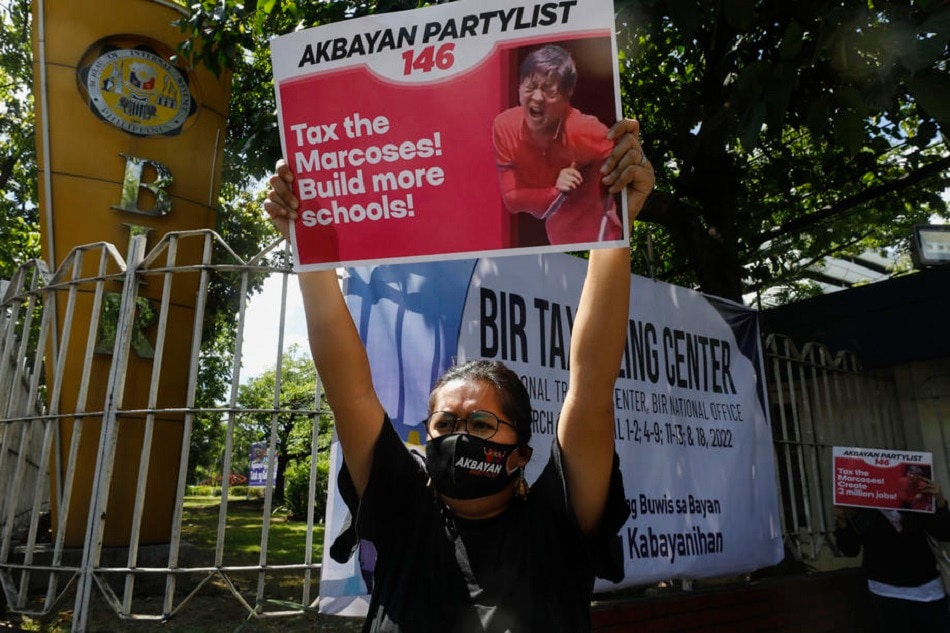 A protester holds a sign outside the Bureau of Internal Revenue (BIR) to call for the immediate collection of taxes owed by the heirs of the late president Ferdinand Marcos, in Quezon City, Metro Manila, Philippines, 31 March 2022. EPA-EFE/ROLEX DELA PENA/File