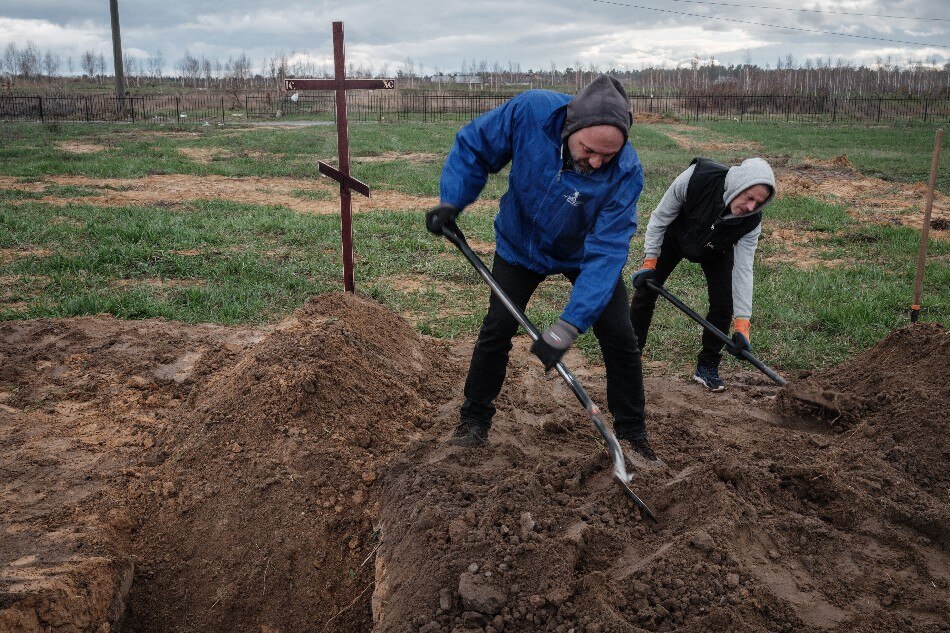 Two residents dig the ground after burying two bodies in the town of Bucha, northwest of Kyiv on April 17, 2022. Yasuyoshi Chiba, AFP/file