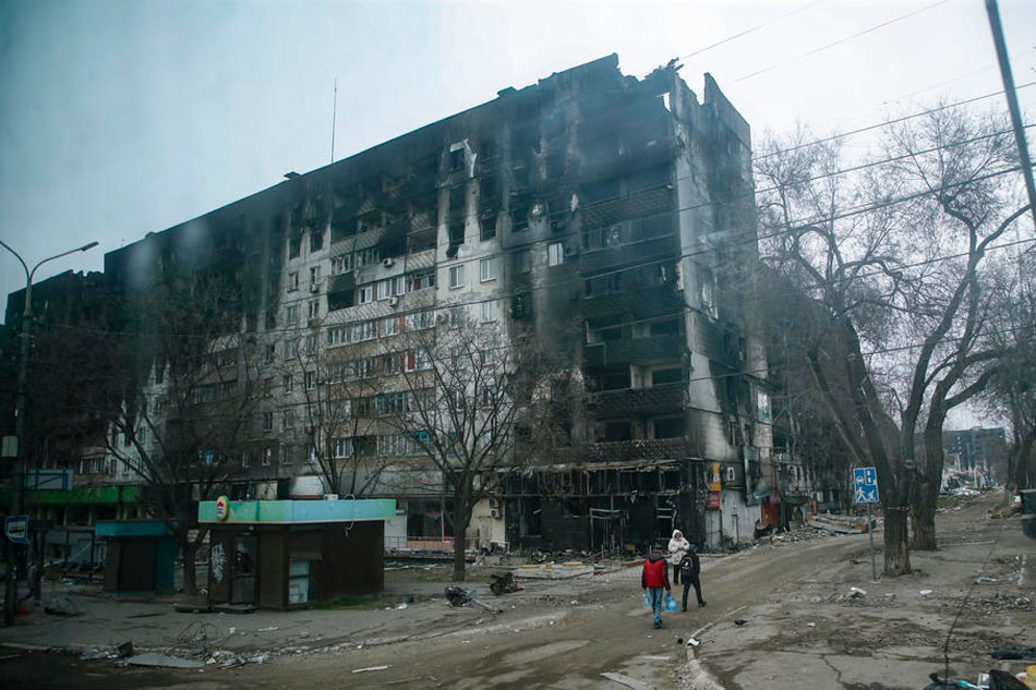 A picture taken during a visit to Mariupol organized by the Russian military shows local people cary water near devesteted and burned apartment building in downtown Mariupol, Ukraine, on April 12, 2022. Sergei Ilnitsky, EPA-EFE/file 