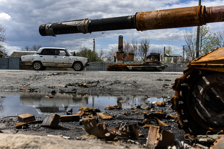A car, damaged by shelling, passes destroyed armored vehicles in Kolychivka village, Chernihiv region, April 27, 2022. Oleg Petrasyuk, EPA-EFE