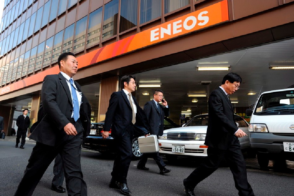 Japanese businessmen walk past Nippon Oil (ENEOS) gasoline station in downtown Tokyo, Japan, 04 December, 2008. Everett Kennedy Brown, EPA-EFE/File