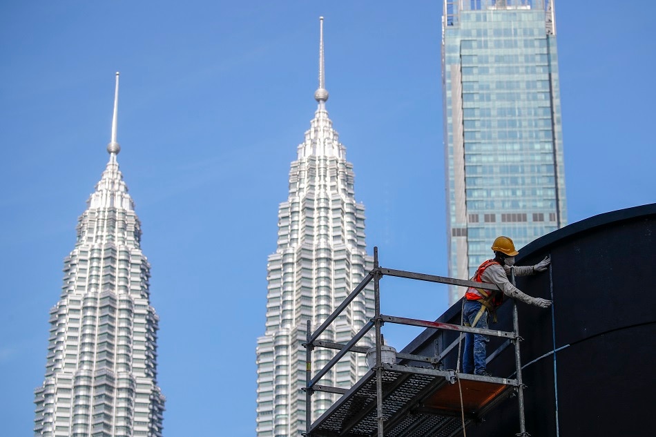 A construction worker is seen against the iconic 'Petronas Twin Towers' in Kuala Lumpur, Malaysia, 28 December 2021. Fazry Ismail, EPA-EFE