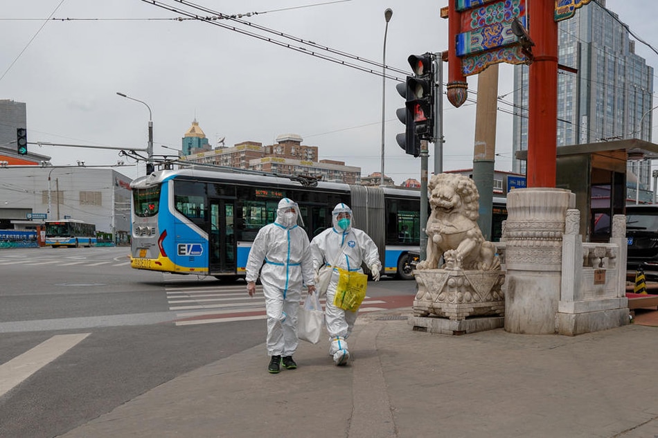 Health workers wearing protective suits walk along a road in Beijing, China, on May 11, 2022. Mark R. Cristino, EPA-EFE 