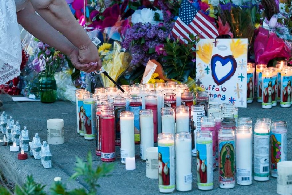 A person lights candles at a memorial for victims near the scene of yesterday's shooting at a Tops Friendly Market grocery store in Buffalo, New York, USA, May 15, 2022. A gunman, who has been identified by authorities as 18-year-old Payton S. Gendron and is in police custody, reportedly opened fire at the market on Saturday afternoon and killed 10 people. Brandon Watson, EPA-EFE 