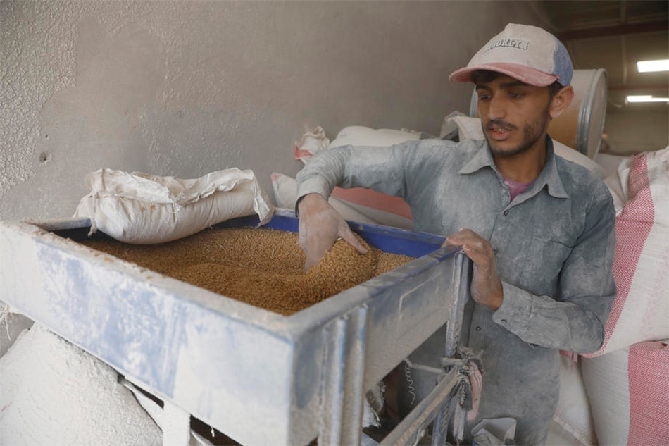 Yemeni worker grinds imported wheat grain at a flour mill in Sana'a, Yemen