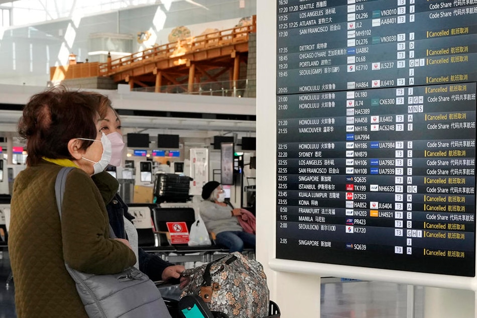 Japanese travelers are checking flight information at the departure terminal of Tokyo International Airport at Haneda in Tokyo, on December 3, 2021. Kimimasa Mayama, EPA-EFE/file