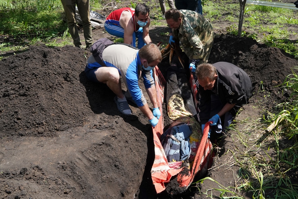 A special team carries out the exhumation of the body of a man reportedly shot in a yard of his house in the Mala Rohan village near Kharkiv, Ukraine, on May 23, 2022. Vasiliy Zhlobsky, EPA-EFE 