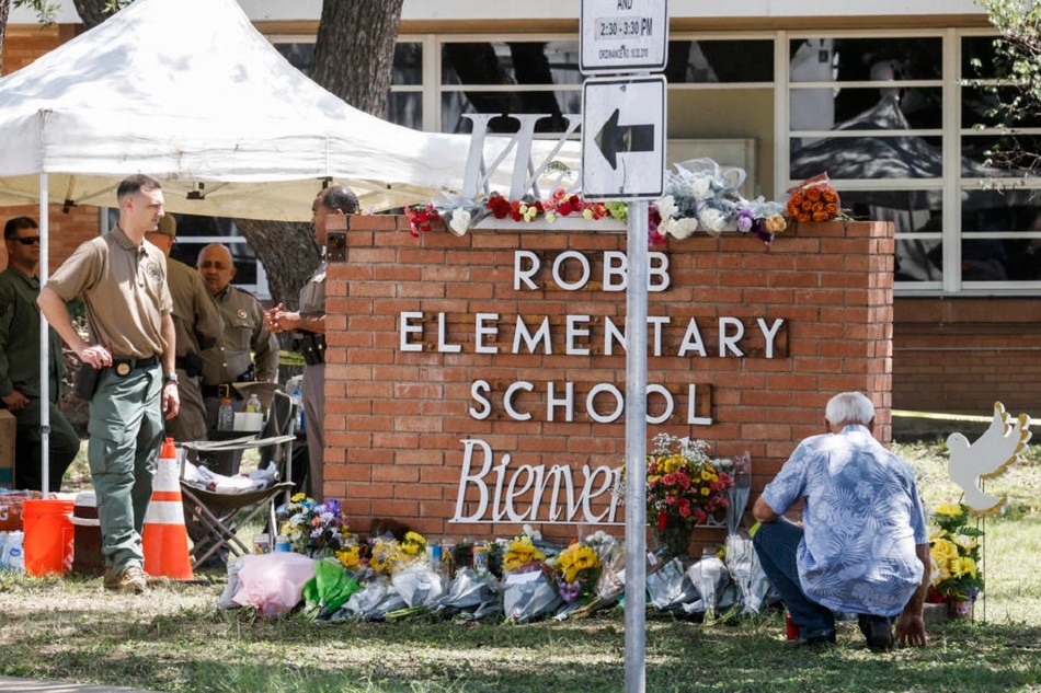A man kneels by a memorial of flowers at the scene of a mass shooting at the Robb Elementary School in Uvalde, Texas, May 25, 2022. Tannen Maury, EPA-EFE