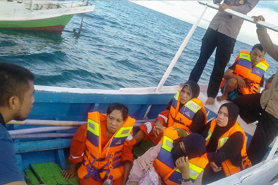 A handout photo made available by the Indonesian national search and rescue agency (BASARNAS) shows survivors sitting on a wooden boat after being rescued from the water off Takalar, South Sulawesi, Indonesia, 28 May 2022. At least 26 people went missing while 17 others had been rescued after a boat with 43 people on board run off fuel and capsized in the water off Sulawesi island. EPA-EFE/BASARNAS / HANDOUT