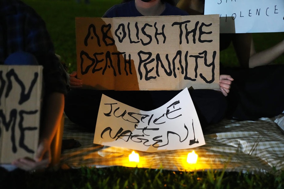 People hold candles and placards during a candlelight vigil against the death penalty for Malaysian national Nagaenthran K. Dharmalingam at the Speakers corner in Hong Lim Park, Singapore, April 25, 2022. How Hwee Young, EPA-EFE/file 