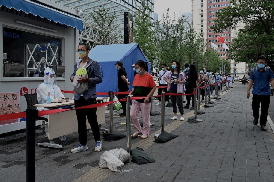 People queue to be tested for the COVID-19 coronavirus at a swab collection site in Beijing on June 13, 2022. Beijing announced 3 rounds of mass testing to quell a 'ferocious' COVID-19 outbreak in the populous Chaoyang district that emerged at a bar in a nightlife and shopping area last week. Noel Celis, AFP