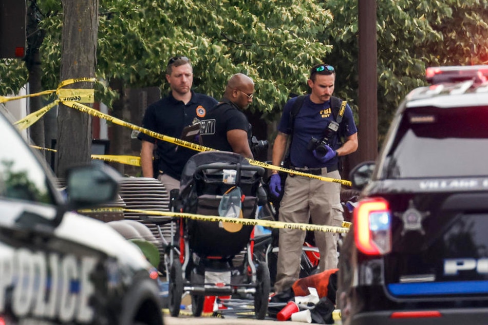 Law enforcement officers investigate the scene of a mass shooting at a 4th of July celebration and parade in Highland Park, Illinois, USA, July 4, 2022. A gunman opened fire as people gathered to watch a Fourth of July parade in Highland Park, Illinois, killing at least 6 people and injuring dozens. Tannen Maury, EPA-EFE