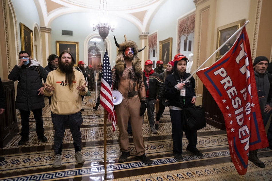 Supporters of US President Donald J. Trump, including 'QAnon Shaman' Jacob Anthony Angeli Chansley (C), stand by the door to the Senate chambers after they breached the US Capitol security in Washington, DC, USA, Jan. 6, 2021. Jim Lo Scalzo, EPA-EFE/File 
