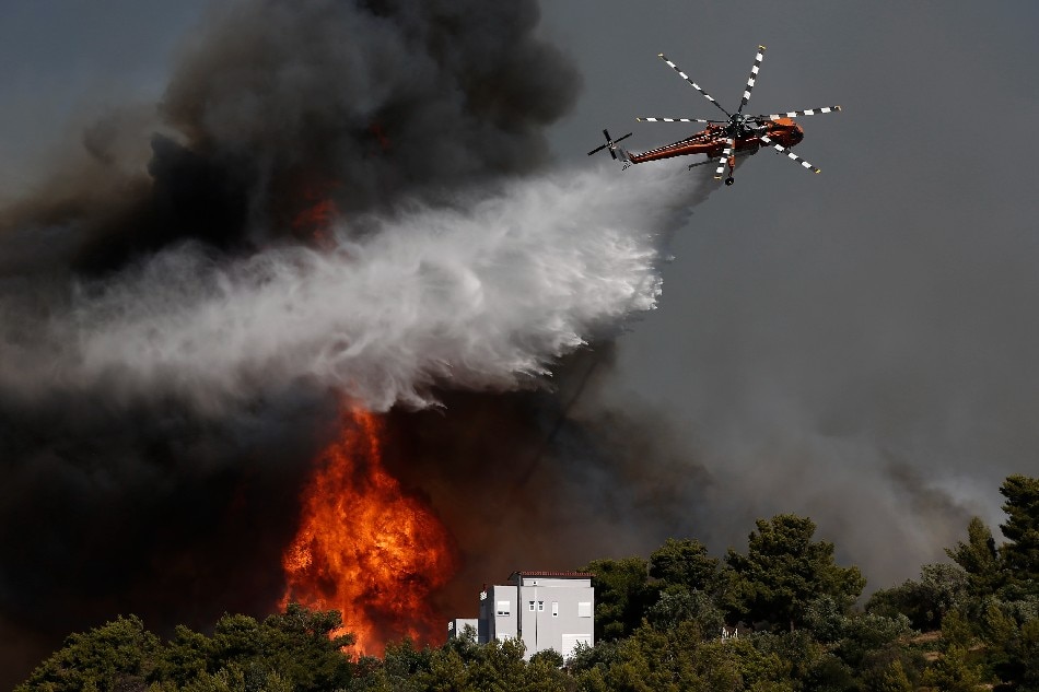 A firefighting helicopter tries to extinguish a wildfire threatening houses at the north-east suburb of Pallini, near Athens, Greece, 20 July 2022. Raging wildfires continued to burn throughout the night and into the early morning hours on 20 July in the northeast suburbs of Athens, with fire fighters and civil protection services engaged in a desperate battle to control flames that were fanned by gale-force winds with high speed, intensity and constantly changing direction. The Hellenic Police have carried out 600 evacuations of citizens to safe locations. Three planes and five helicopters joined the battle, alongside 485 firefighters, 120 fire engines and 28 ground teams operating below, assisted by volunteer fire fighters, local authority water tanker trucks and heavy machinery. EPA-EFE/YANNIS KOLESIDIS