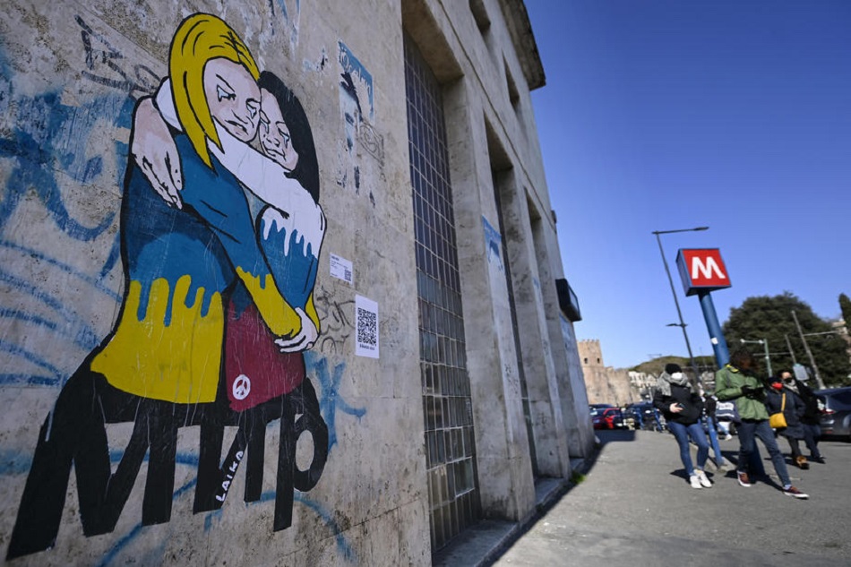 An anti-Ukraine war mural by Italian street artist known by the name of Laika depicting a hug between two women, one dressed in the Russian, the other in the Ukrainian national colors, respectively, above the word MIR (Peace), is painted on a wall in Rome, Italy, on International Women's Day, March 8, 2022. Riccardo Antimiani, EPA-EFE/file